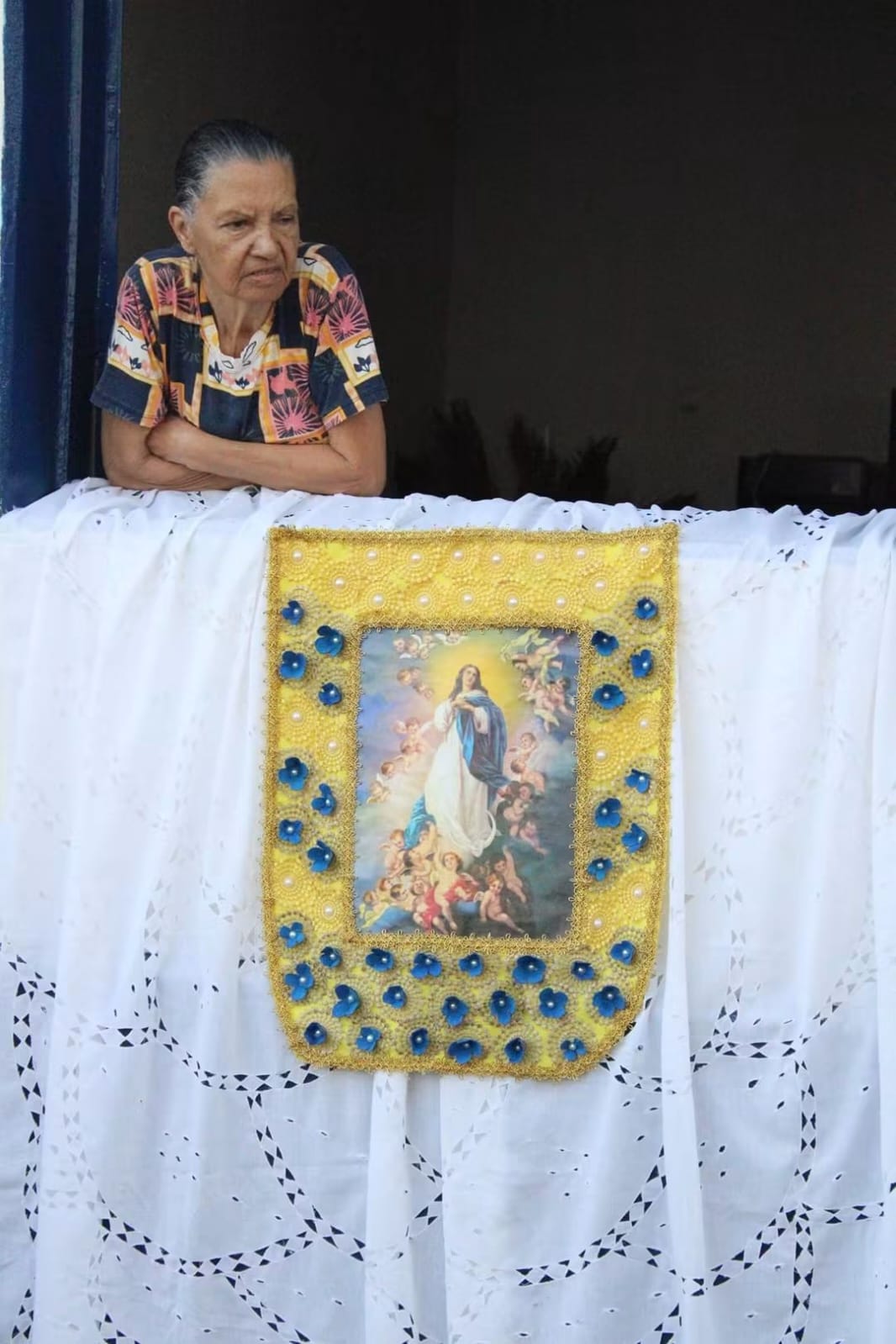 Devota junto a um tecido bordado com a imagem da Imaculada Conceição